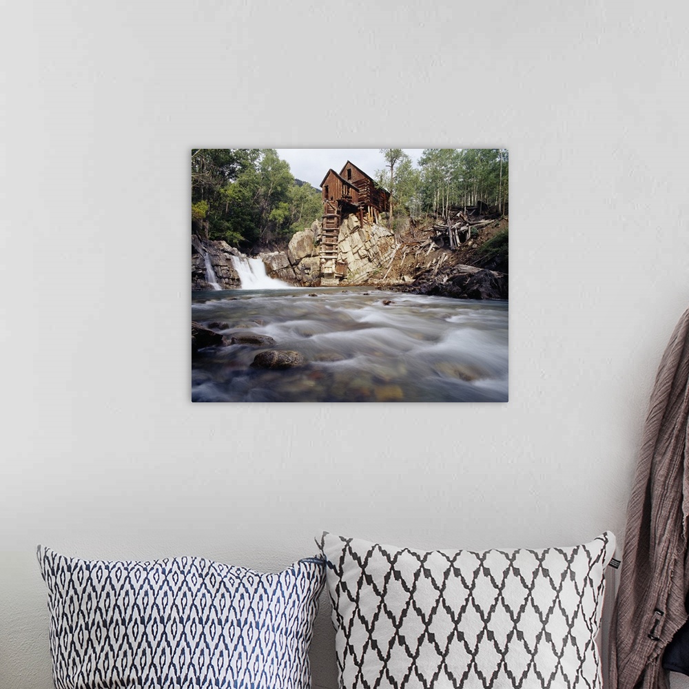 A bohemian room featuring Photograph of old log cabin sitting on top of rocky hill with rushing stream below.