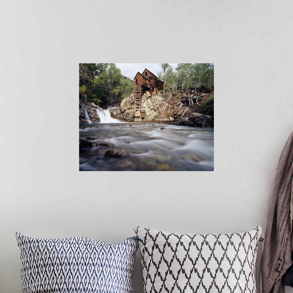 A bohemian room featuring Photograph of old log cabin sitting on top of rocky hill with rushing stream below.