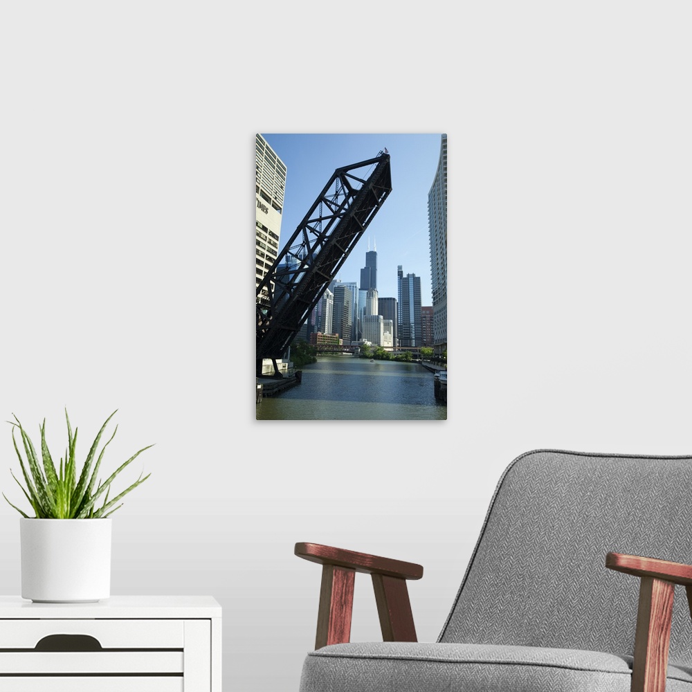 A modern room featuring Vertical wall docor of a big bridge raising up on the Chicago River with the Willis Tower in the ...