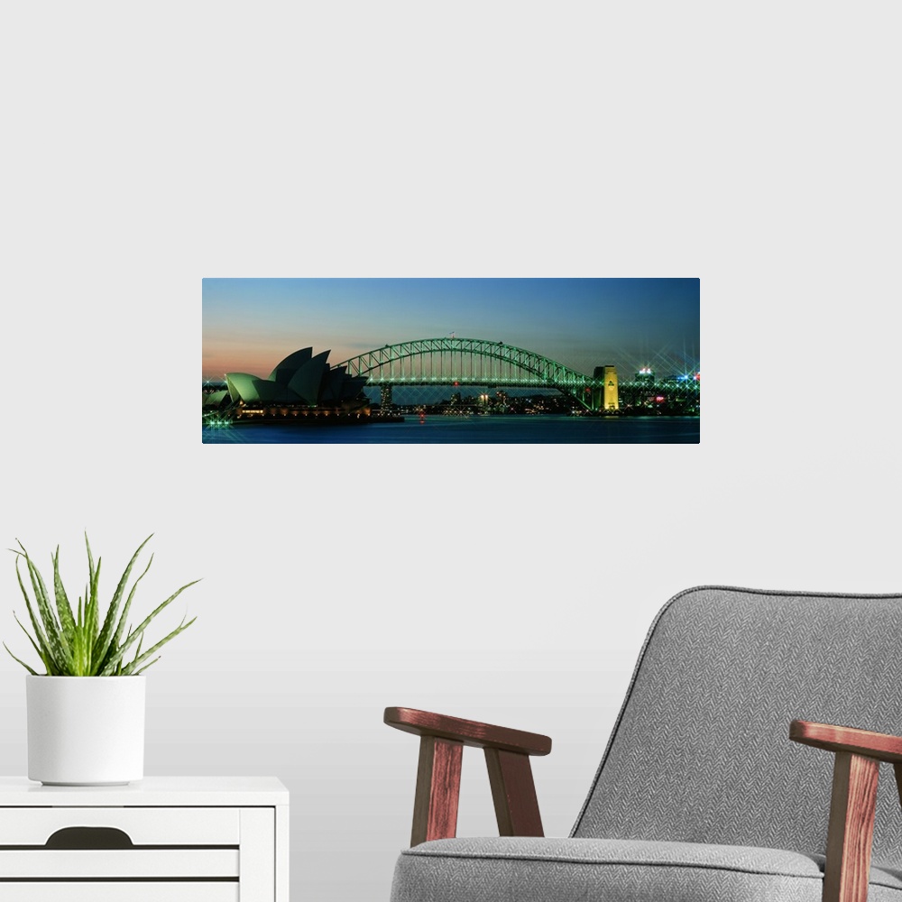 A modern room featuring Long horizontal canvas of the Opera House in Sydney lit up at dusk with a bridge running behind it.