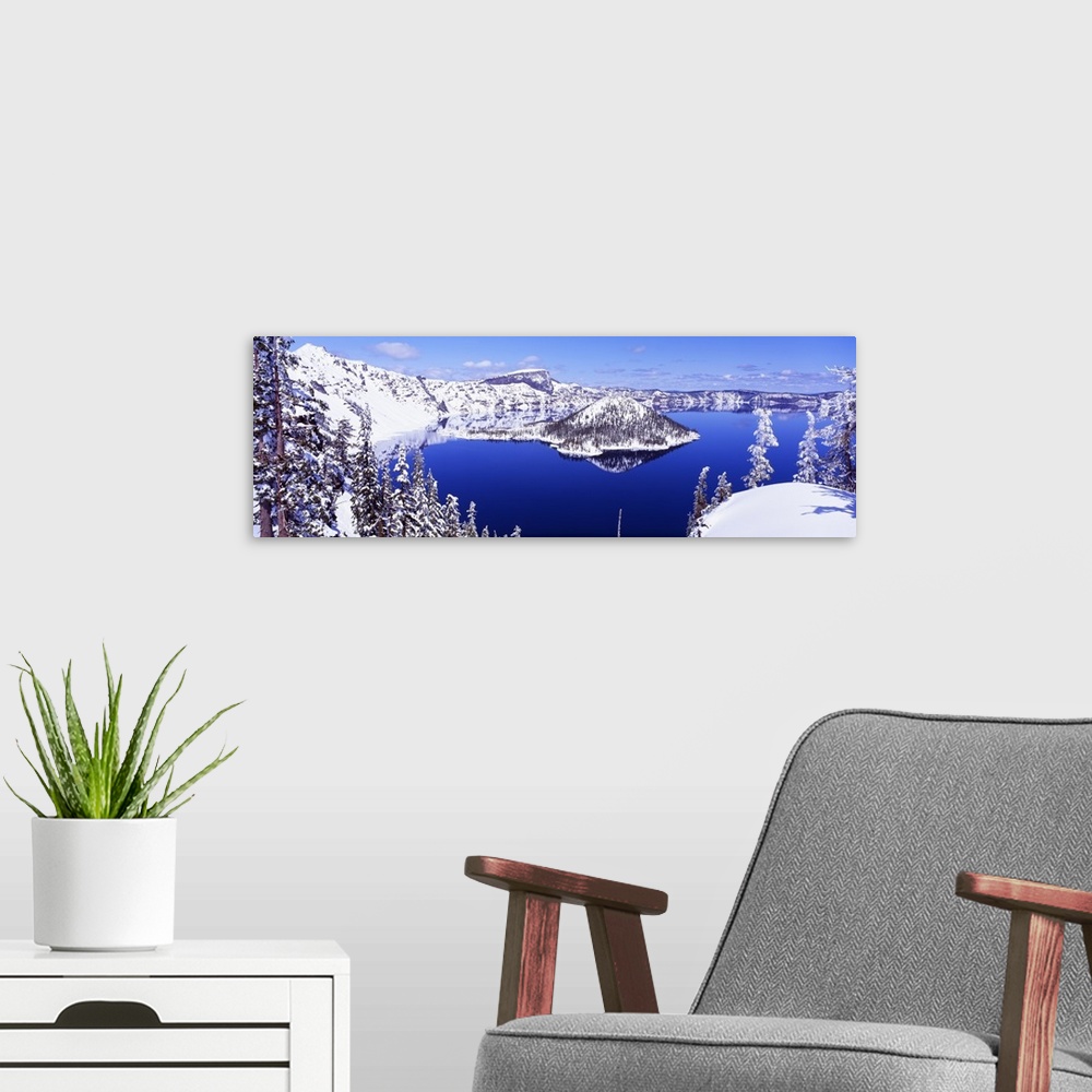 A modern room featuring Wide angle shot taken of Crater lake looking out toward snow covered mountains and pine trees.