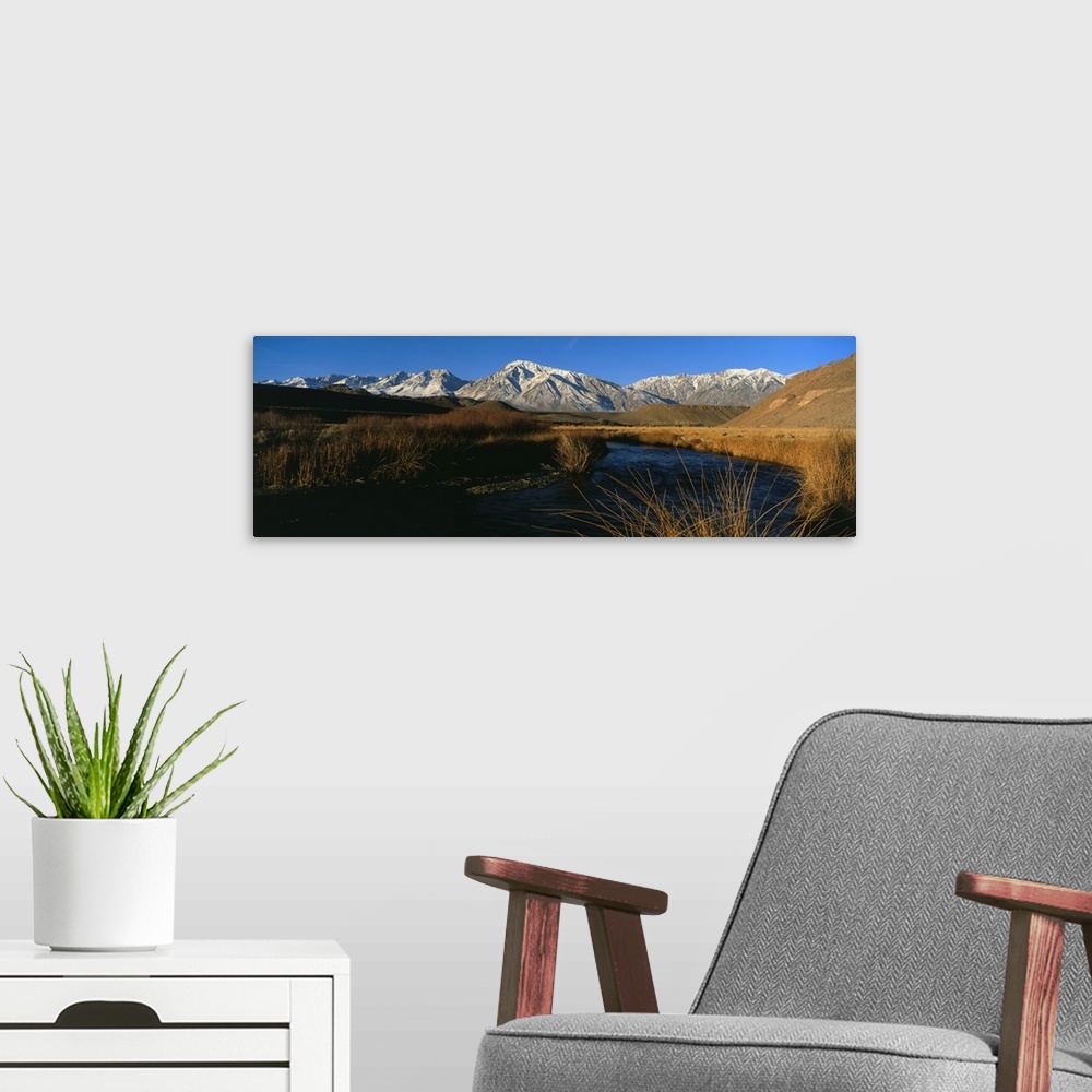 A modern room featuring A mountain range lines the background of this panoramic photograph with a river in the foreground...