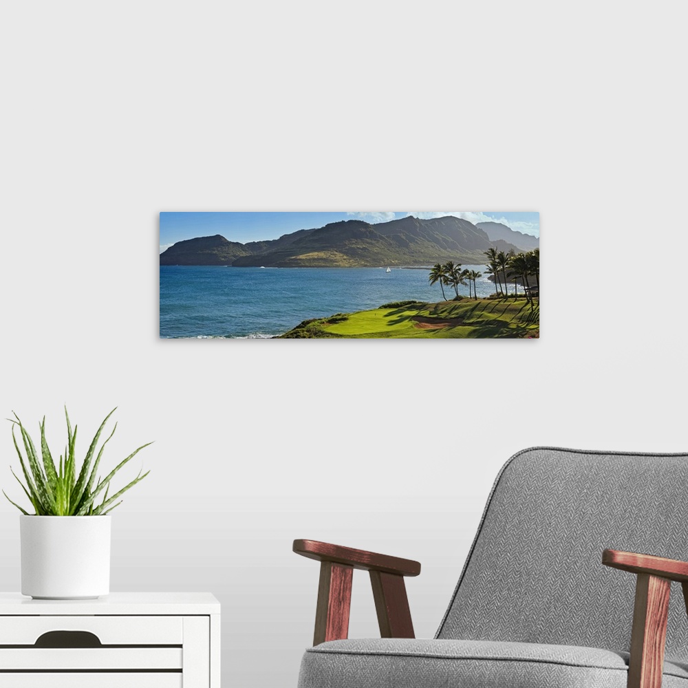 A modern room featuring Panoramic photograph taken from a golf course of a large mountain across a lagoon in Hawaii.