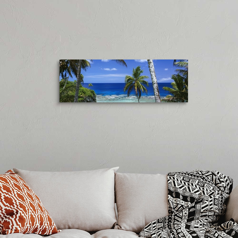 A bohemian room featuring Giant, panoramic photograph of palm trees on the beach of Nive Island, in front of the deep blue ...
