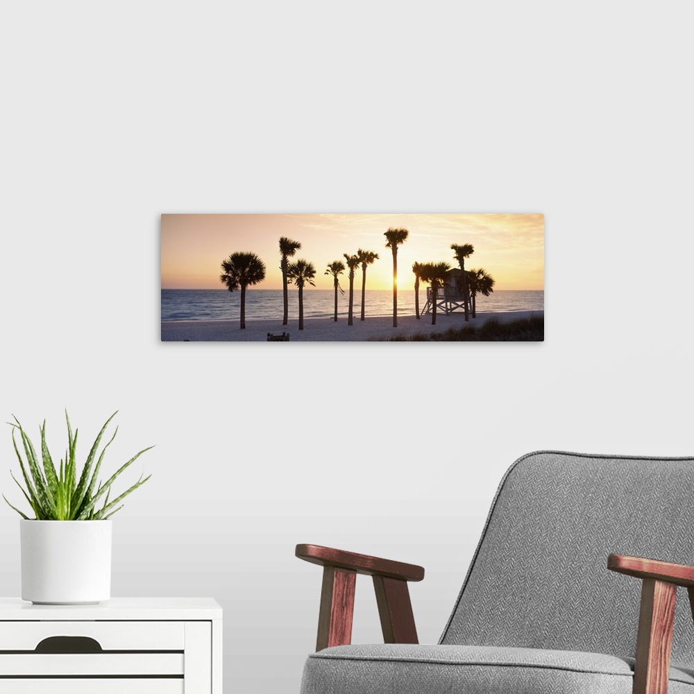 A modern room featuring A large panoramic piece of palm trees on the beach with a lifeguard house in front of them. The o...