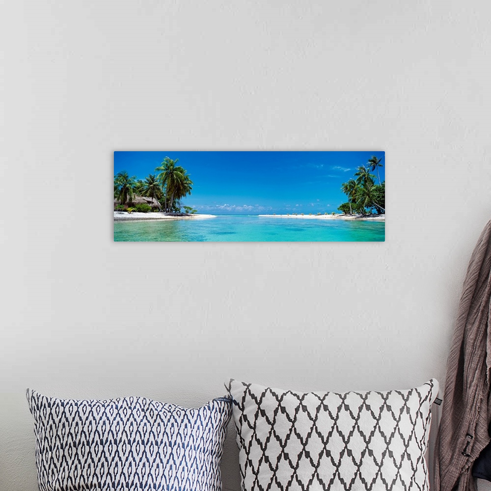 A bohemian room featuring A panoramic photograph of a tropical lagoon surrounded by trees and huts.