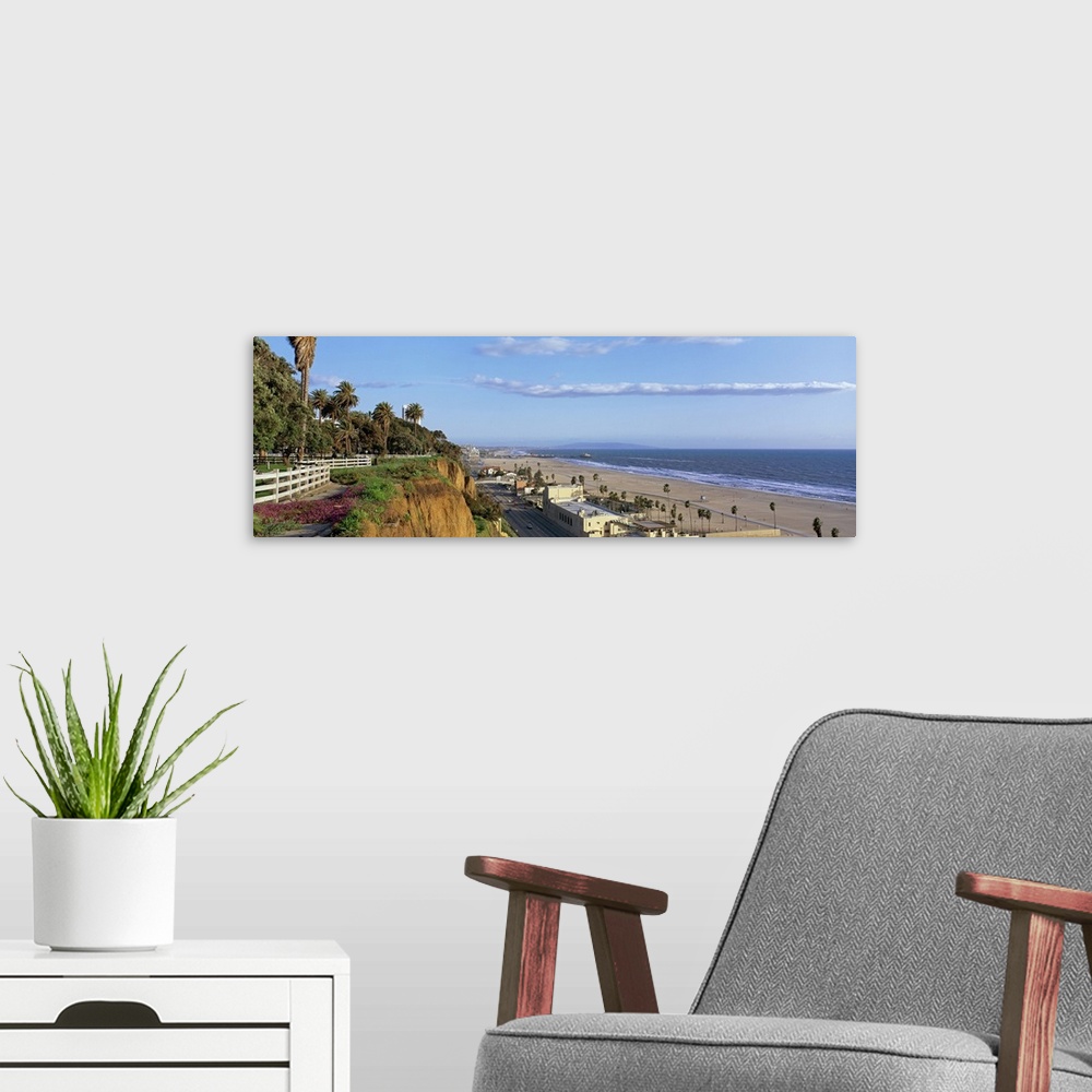 A modern room featuring Panoramic photograph of cliff overlooking shoreline filled with buildings and palm trees under a ...
