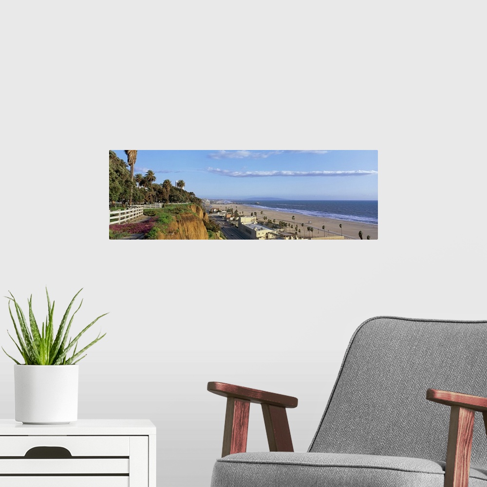 A modern room featuring Panoramic photograph of cliff overlooking shoreline filled with buildings and palm trees under a ...