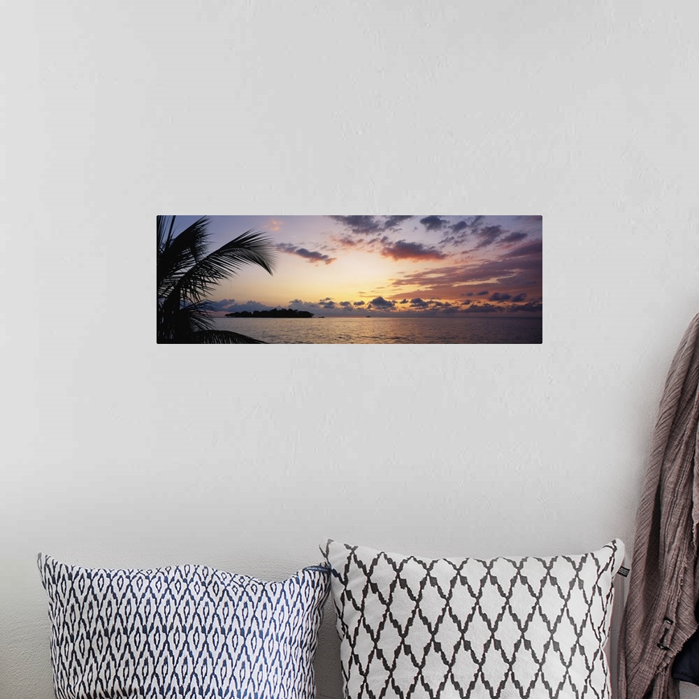A bohemian room featuring Wide angle photograph of a cloudy ocean sunset with the silhouette of a palm tree in the foregrou...
