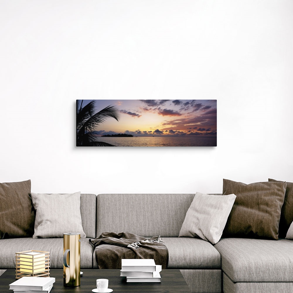 A traditional room featuring Wide angle photograph of a cloudy ocean sunset with the silhouette of a palm tree in the foregrou...