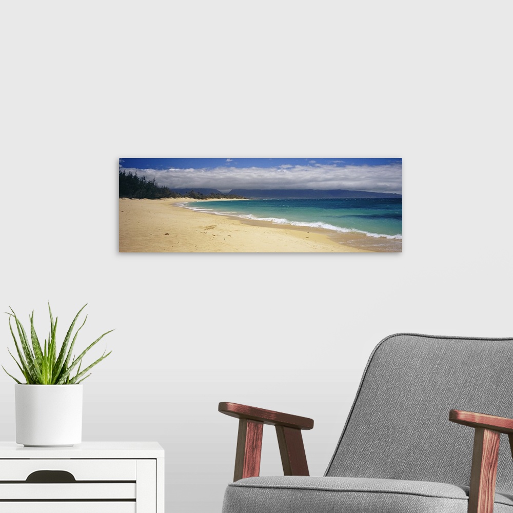 A modern room featuring Wide angle photograph on a large wall hanging of clear blue waters along the beach in Maui, Hawai...