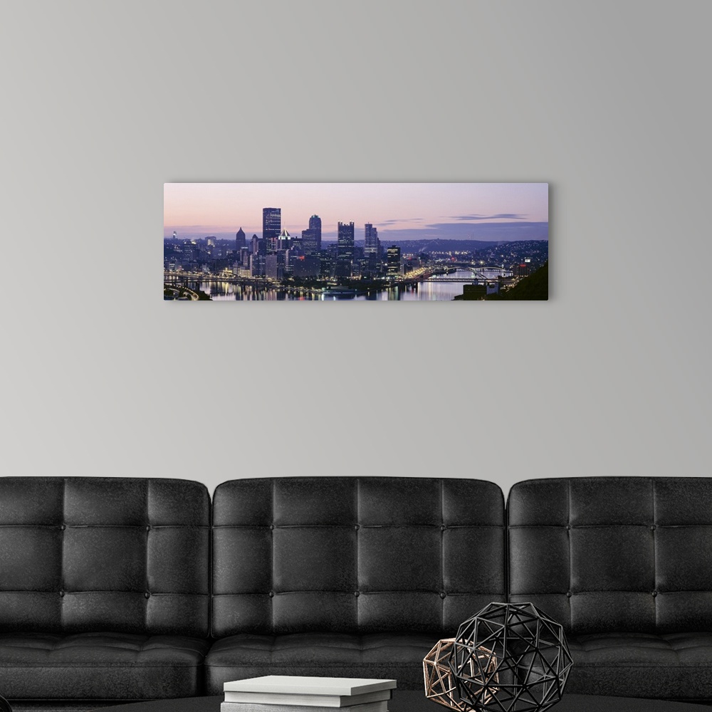 A modern room featuring Panoramic photograph of skyline and waterfront lit up at sunset.