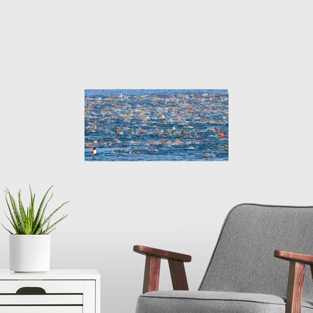 A modern room featuring Horizontal photo on canvas of triathletes swimming in the ocean during the Ironman Kona race.