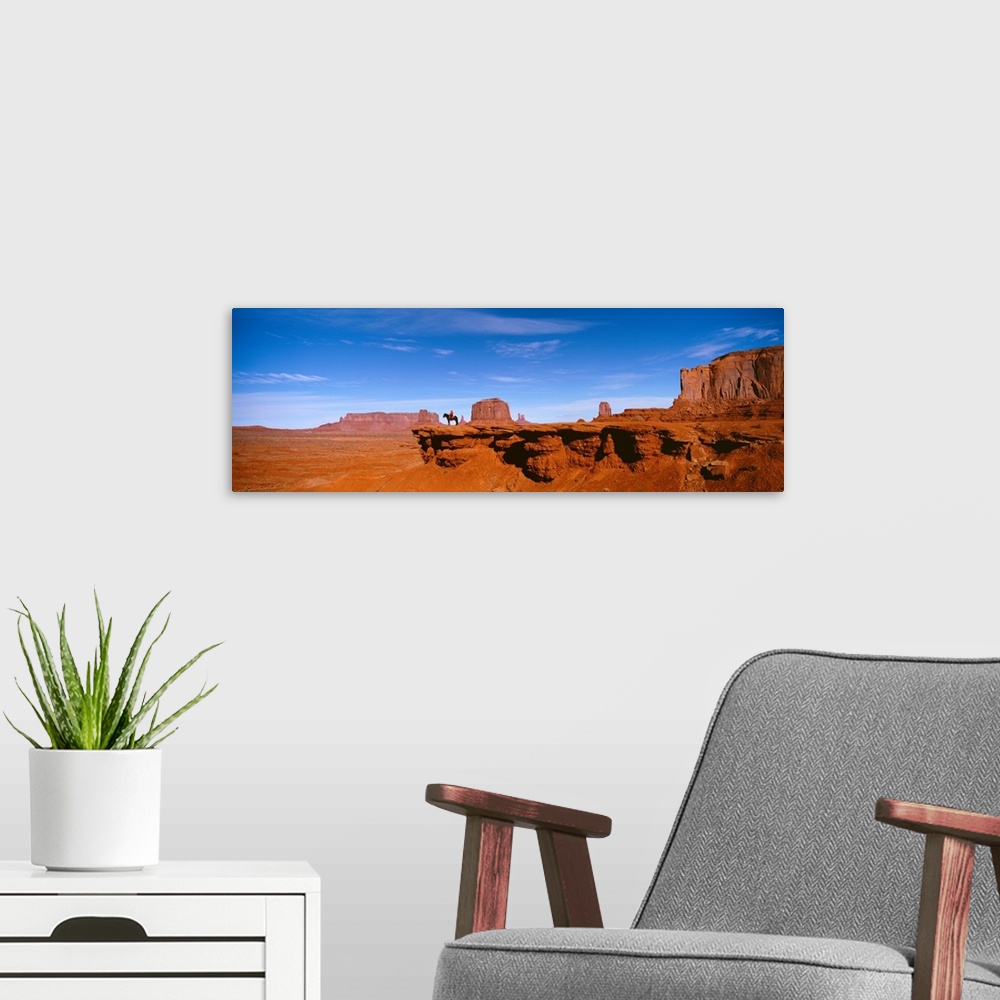 A modern room featuring A man on a horse at the edge of a cliff overlooking the arid desert of Monument Valley on a clear...