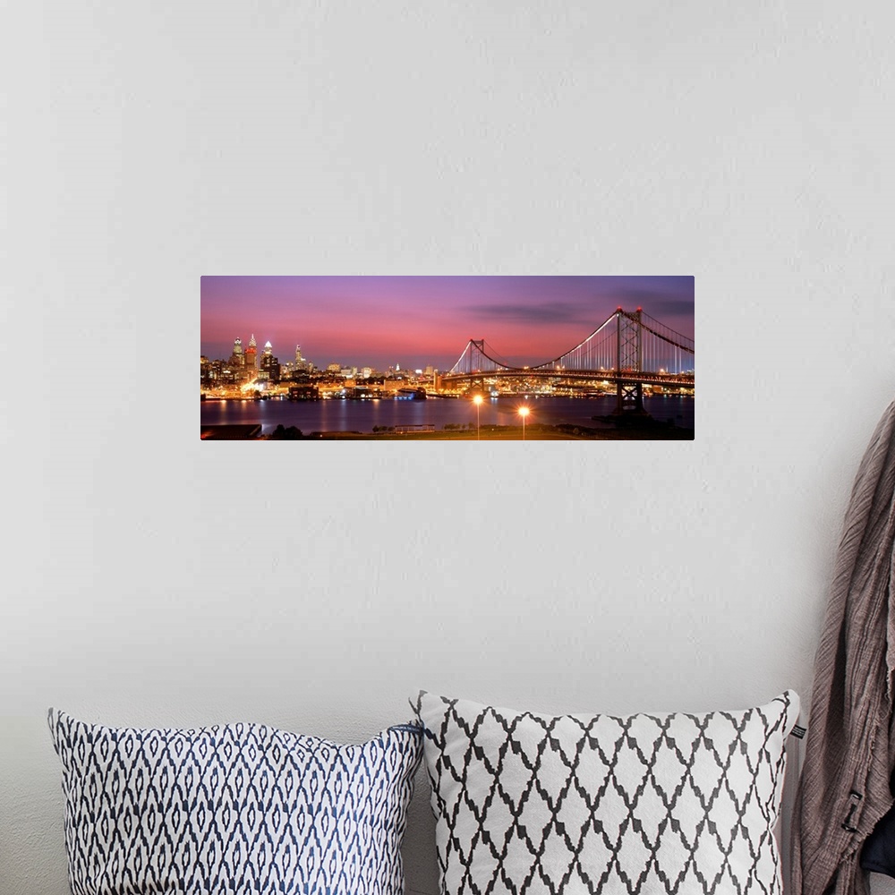 A bohemian room featuring Oversized panoramic artwork of a night time photograph of the Benjamin Franklin Bridge leading to...