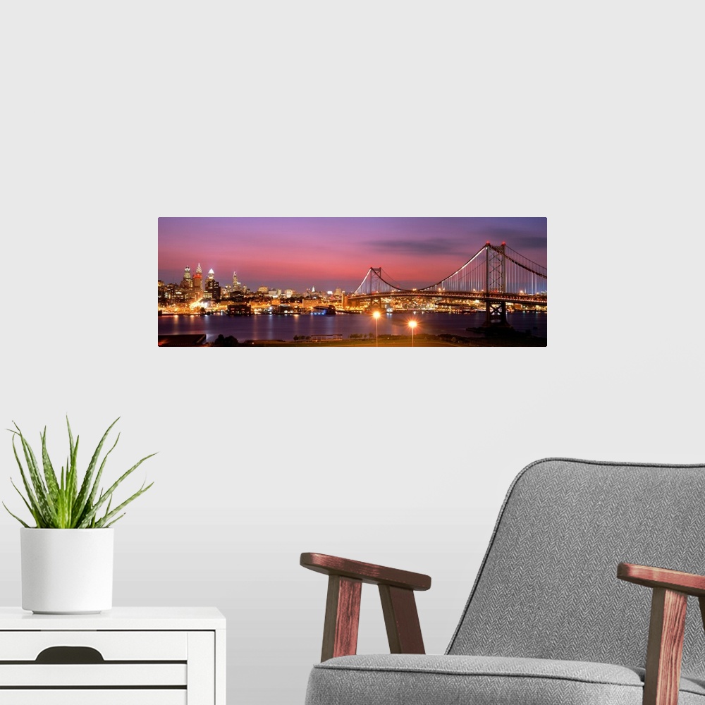 A modern room featuring Oversized panoramic artwork of a night time photograph of the Benjamin Franklin Bridge leading to...
