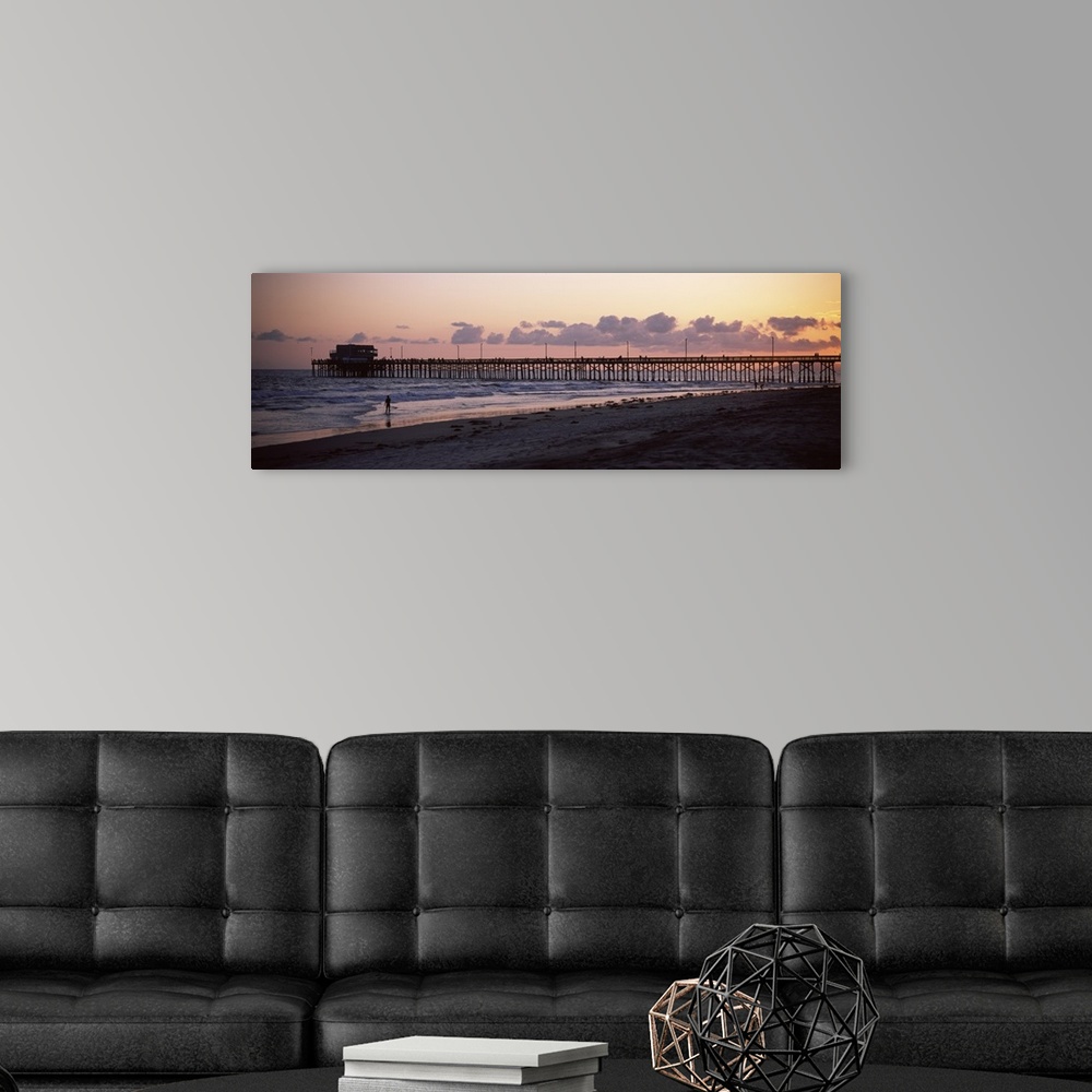 A modern room featuring A beach board walk extends out into the ocean in this landscape photograph of the sun setting on ...