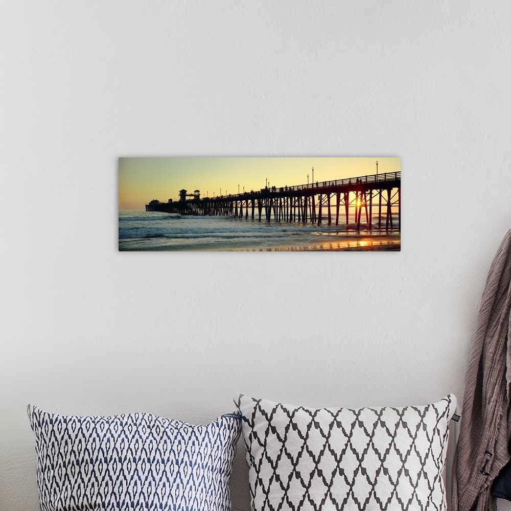 A bohemian room featuring Panoramic wall docor of the silhouette of a pier reaching into the ocean surf at sunset.