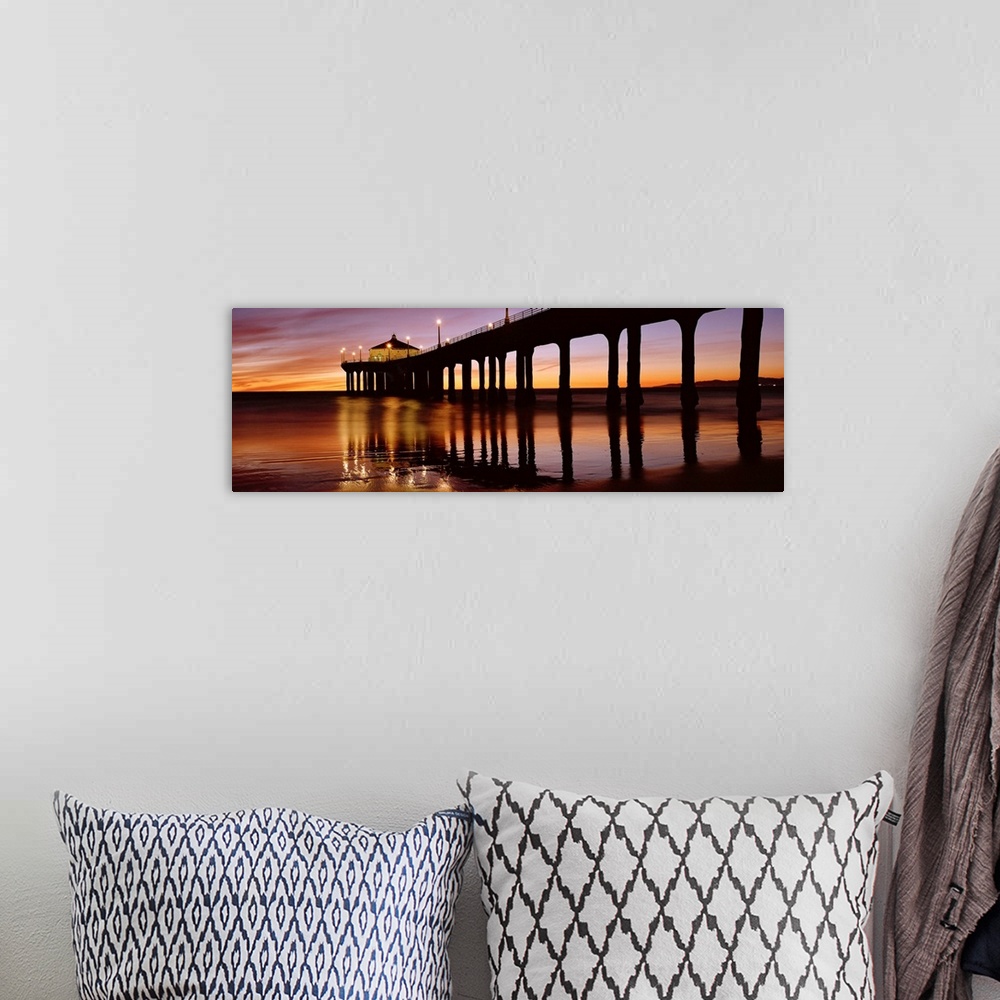 A bohemian room featuring A panoramic photograph of the silhouette of a long pier over the ocean at sunset.