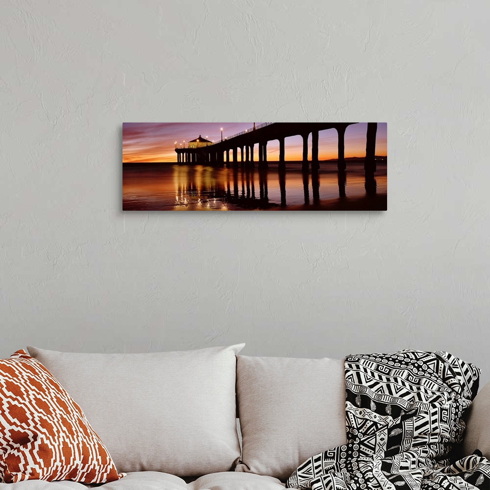 A bohemian room featuring A panoramic photograph of the silhouette of a long pier over the ocean at sunset.