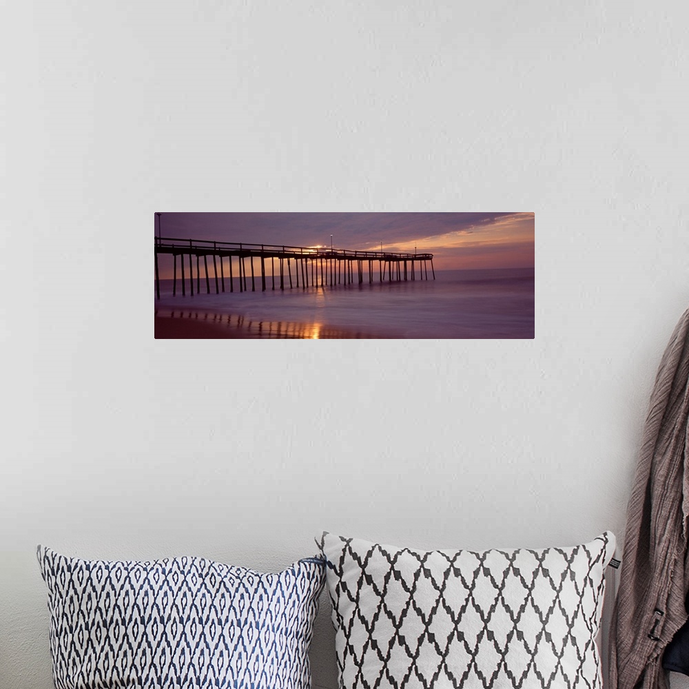 A bohemian room featuring Panoramic photograph of wooden dock stretching into ocean at dusk under a dark cloudy sky.