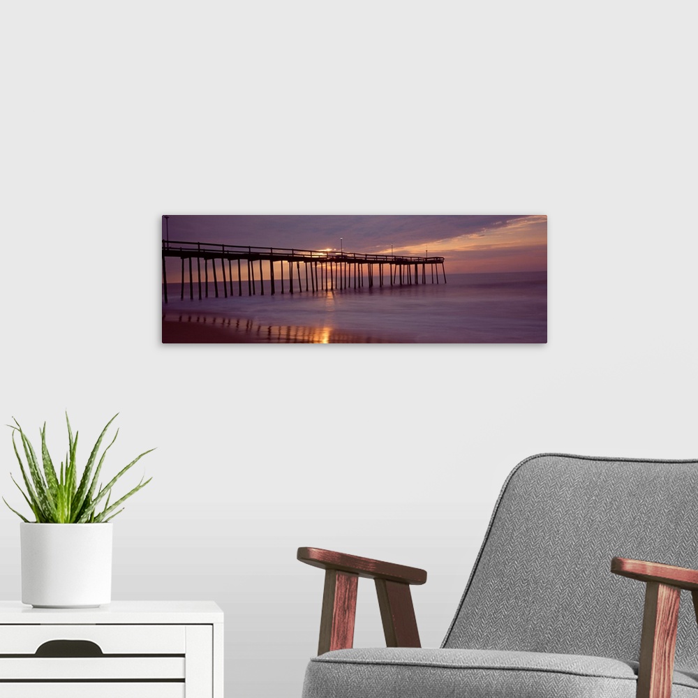 A modern room featuring Panoramic photograph of wooden dock stretching into ocean at dusk under a dark cloudy sky.