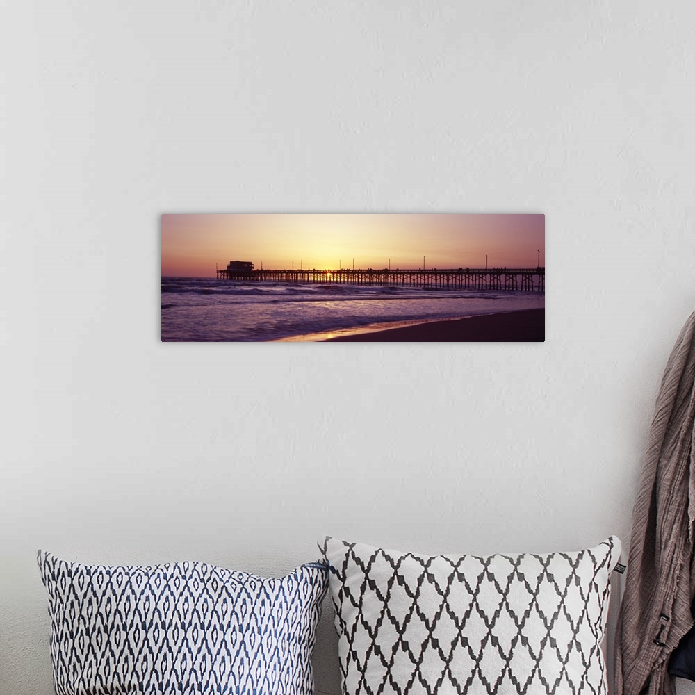 A bohemian room featuring Panoramic photograph of the sunset that can barely be seen behind a long pier that reaches far ou...