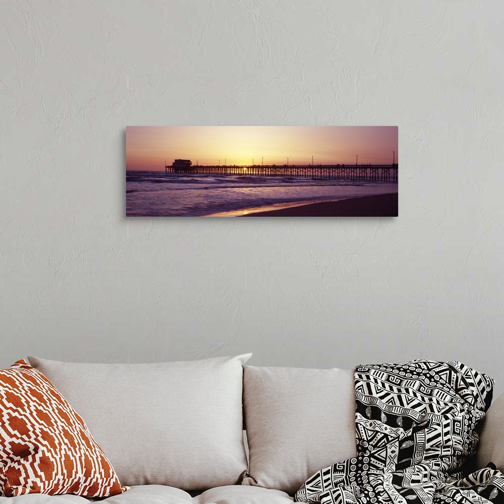 A bohemian room featuring Panoramic photograph of the sunset that can barely be seen behind a long pier that reaches far ou...