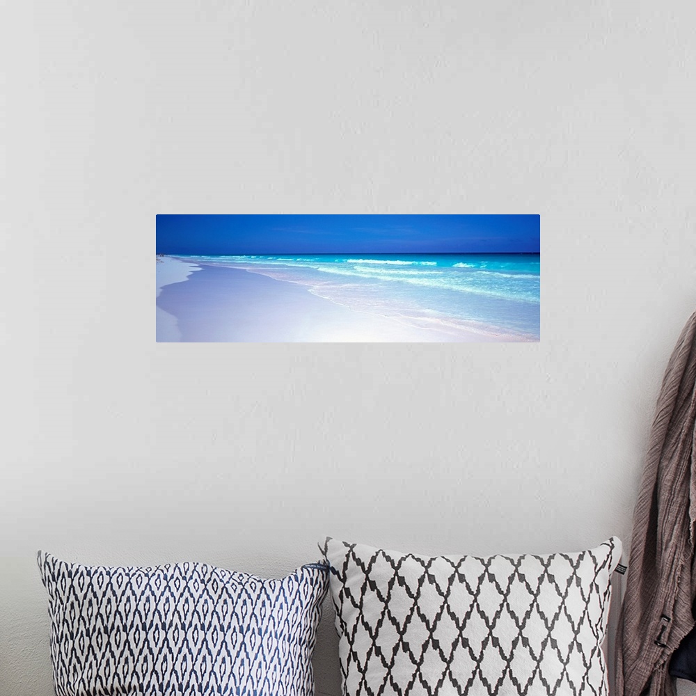 A bohemian room featuring A panoramic wall art picture of a tropical beach with flawless sand and a clear horizon as waves ...