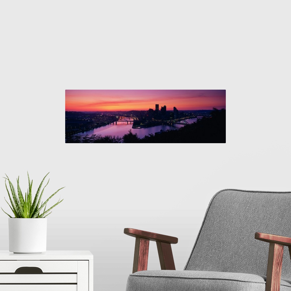 A modern room featuring Oversized, landscape photograph of the distant skyline of Pittsburgh, Pennsylvania lit up, beneat...