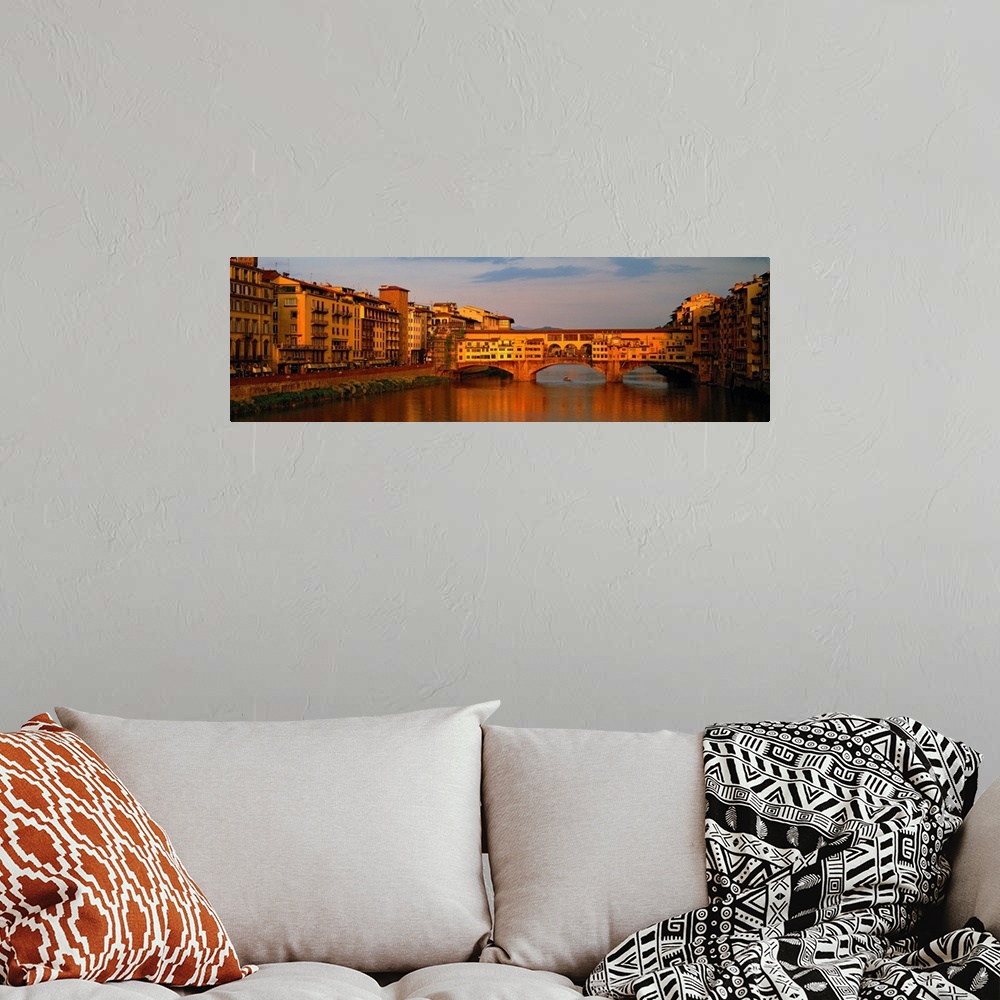 A bohemian room featuring Wide angle photograph of buildings alongside the Arno River, with a view of he Ponte Vecchio brid...