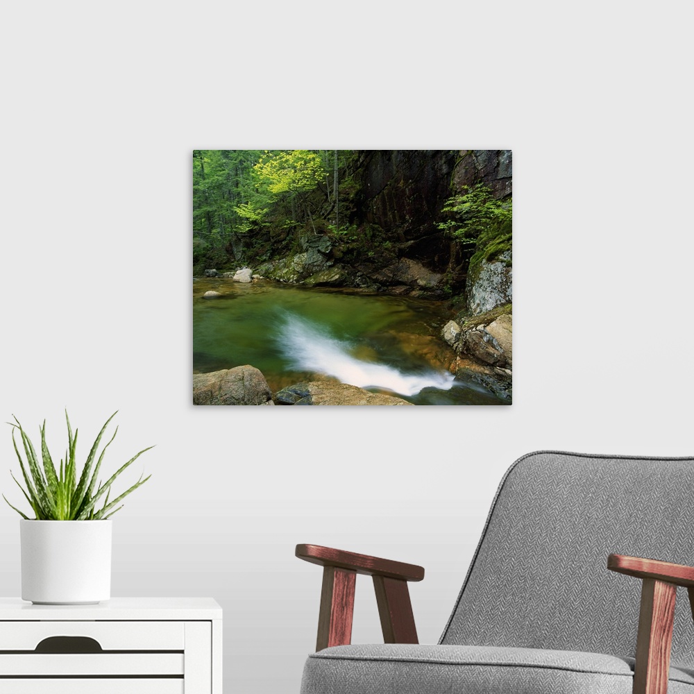 A modern room featuring Large horizontal photograph of a pool of water at the bottom of Sabbaday Falls, surrounded by roc...