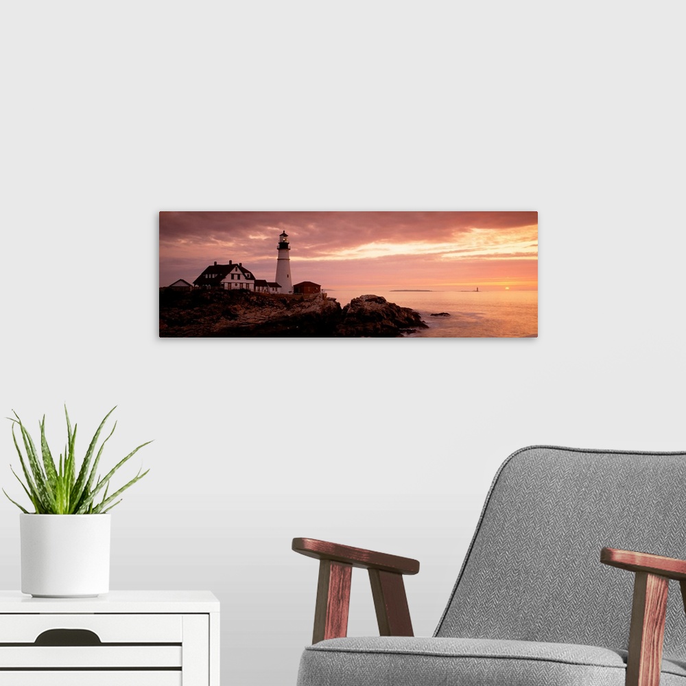 A modern room featuring Panoramic photograph displays the dim light of the sun as it covers the rocky shores of a beach t...