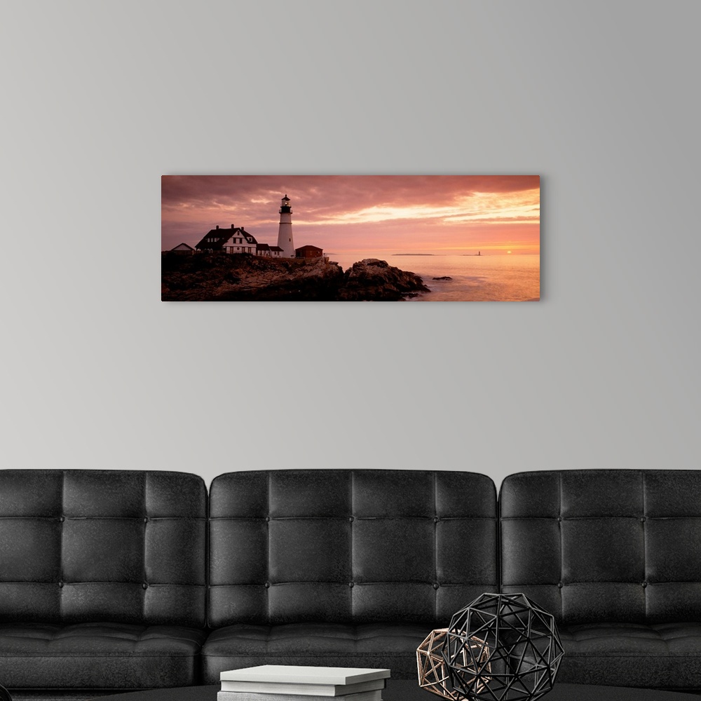 A modern room featuring Panoramic photograph displays the dim light of the sun as it covers the rocky shores of a beach t...