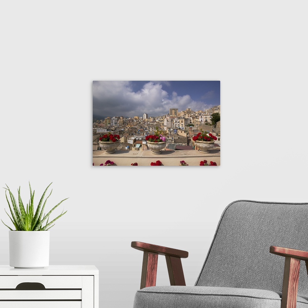 A modern room featuring Canvas photo print of three flowers planted in pots along a balcony with an Italian city in the d...