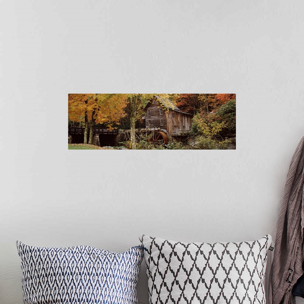 A bohemian room featuring Wide angle view of an old mill surrounded by trees and foliage in the autumn. A small bridge is s...