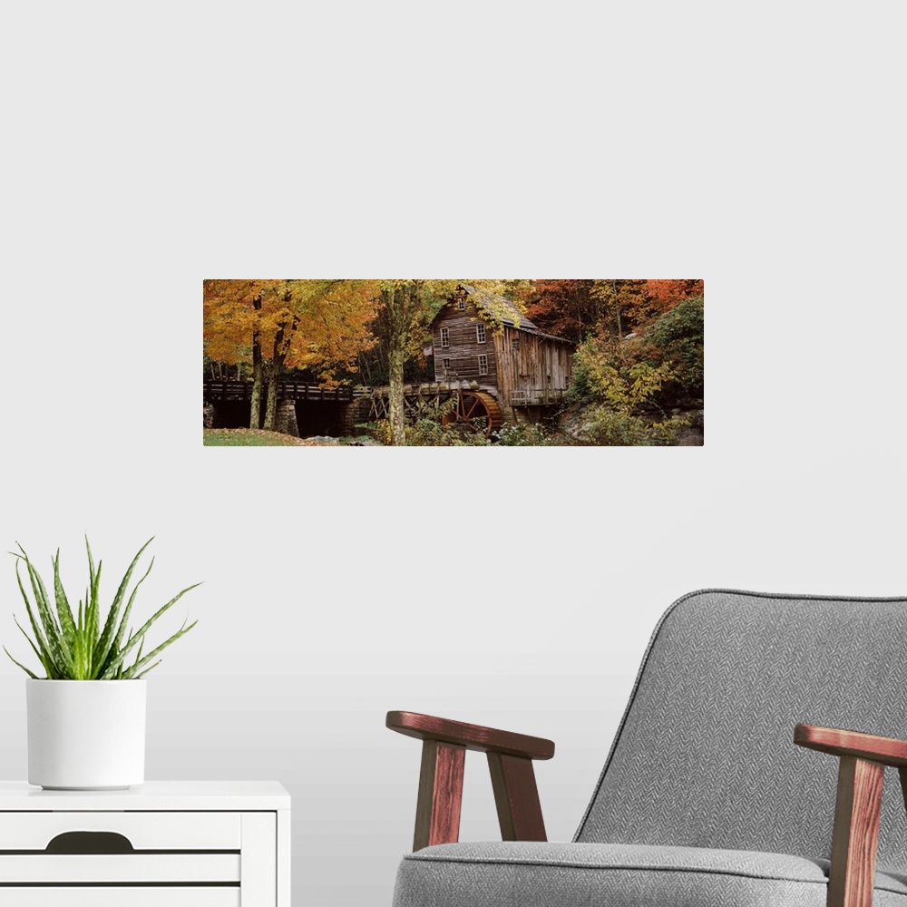 A modern room featuring Wide angle view of an old mill surrounded by trees and foliage in the autumn. A small bridge is s...