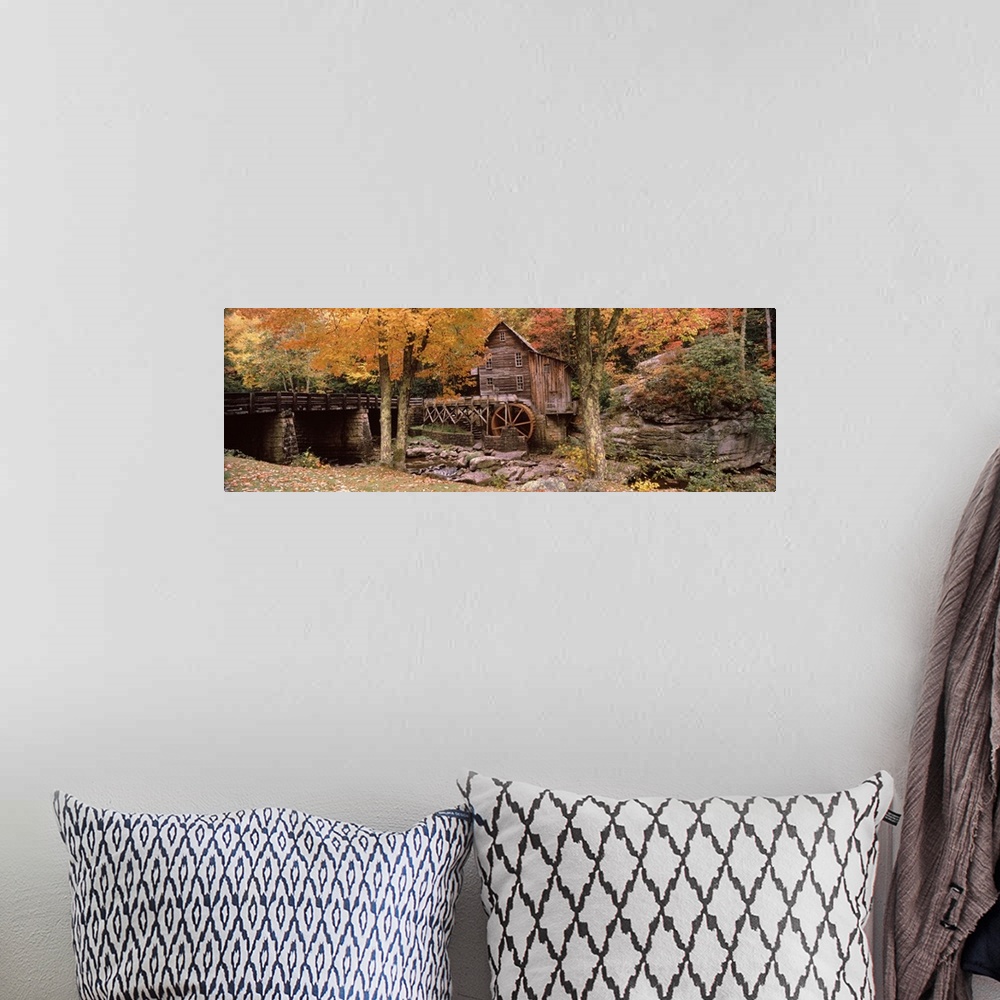 A bohemian room featuring Panoramic photograph of old stone bridge leading to water mill located in a fall forest.