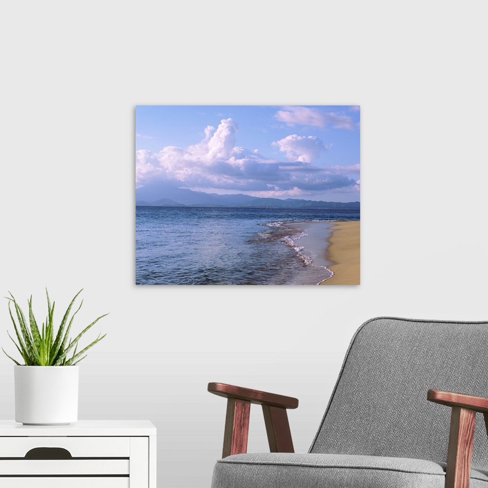 A modern room featuring Scenic photograph of the calm sea and beach in the late afternoon under large clouds in the Carib...
