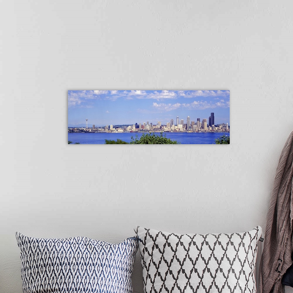 A bohemian room featuring A panoramic photograph is taken of the Seattle skyline across a large body of water with foliage ...