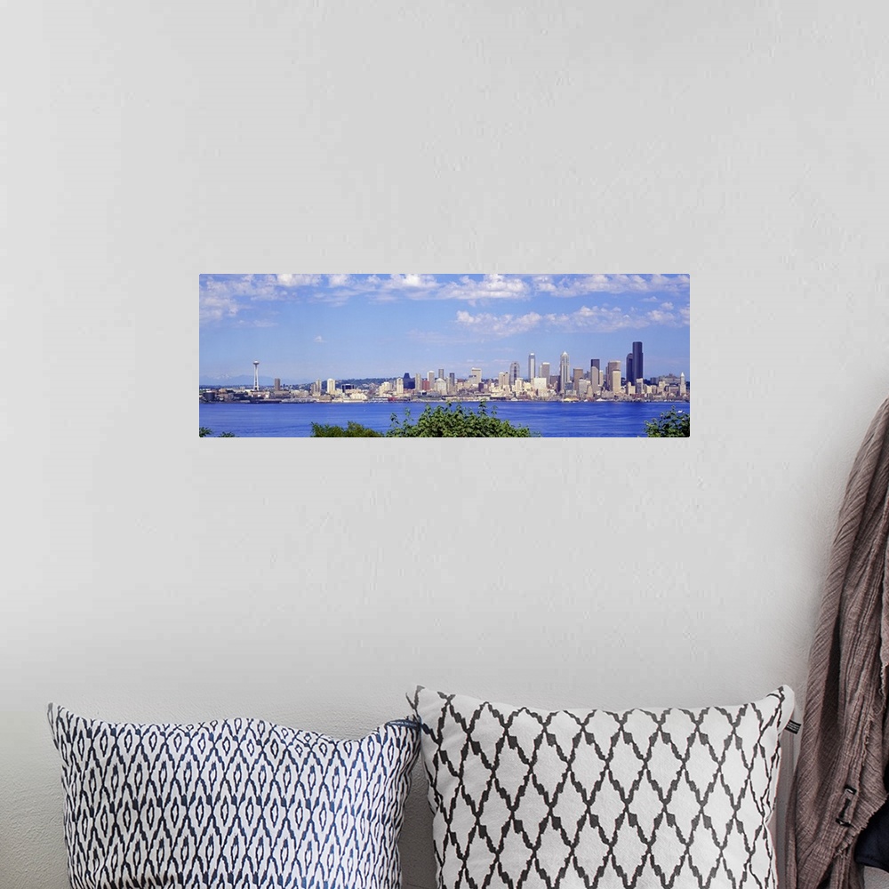 A bohemian room featuring A panoramic photograph is taken of the Seattle skyline across a large body of water with foliage ...