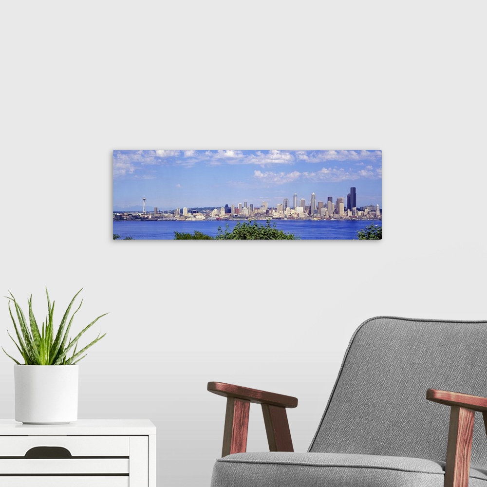 A modern room featuring A panoramic photograph is taken of the Seattle skyline across a large body of water with foliage ...