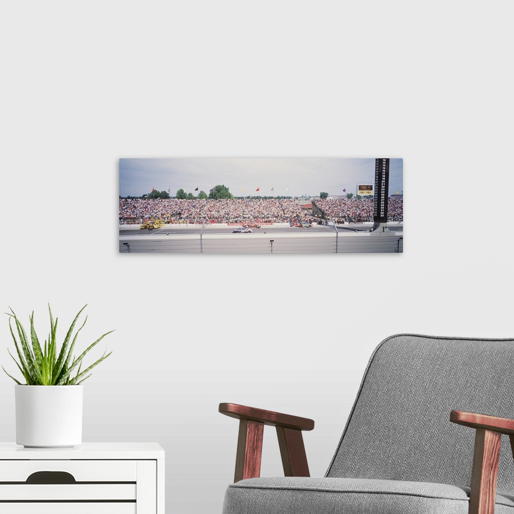 A modern room featuring Panoramic photograph taken inside a race track. Cars are shown speeding along with a packed crowd...