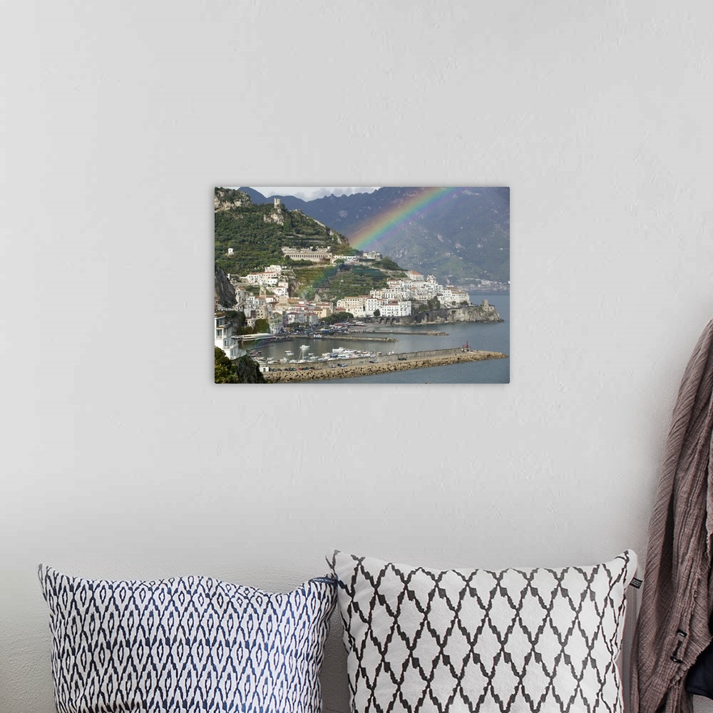 A bohemian room featuring This is a picture of a rainbow over a town off a coast in Italy. Large white buildings line the w...