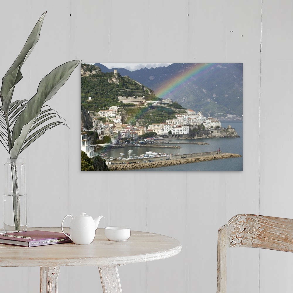 A farmhouse room featuring This is a picture of a rainbow over a town off a coast in Italy. Large white buildings line the w...