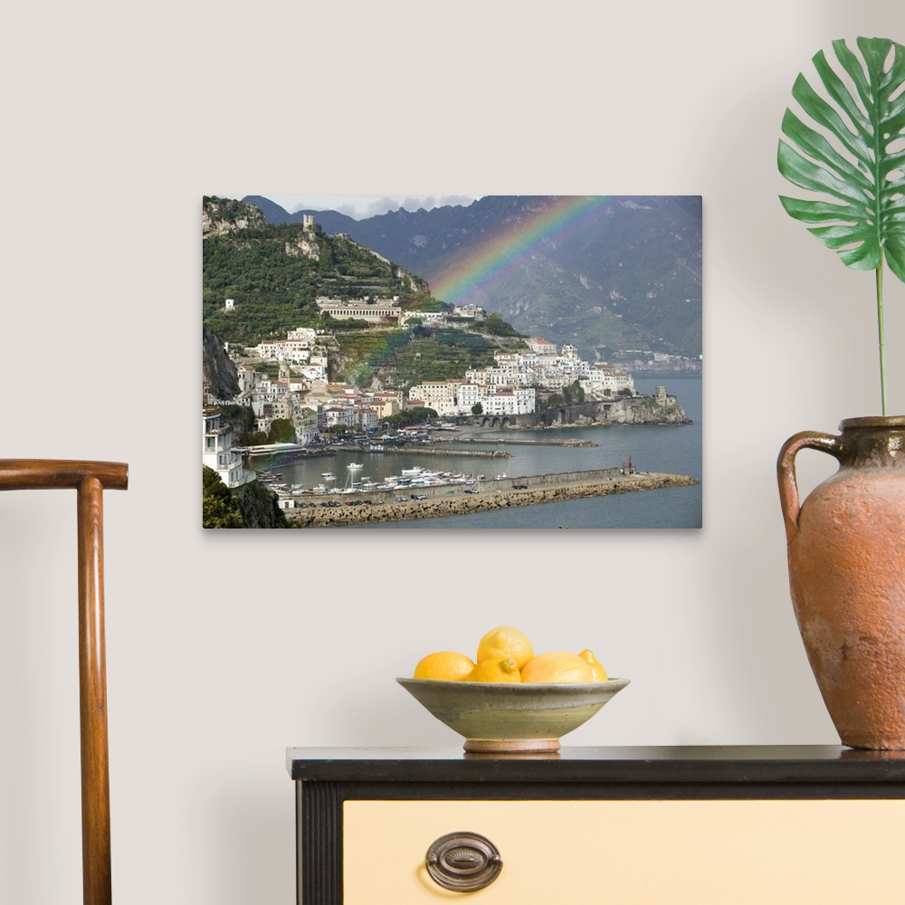 A traditional room featuring This is a picture of a rainbow over a town off a coast in Italy. Large white buildings line the w...