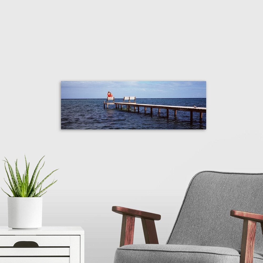 A modern room featuring Rear view of mother and her daughter sitting on a bench at a pier, Belize