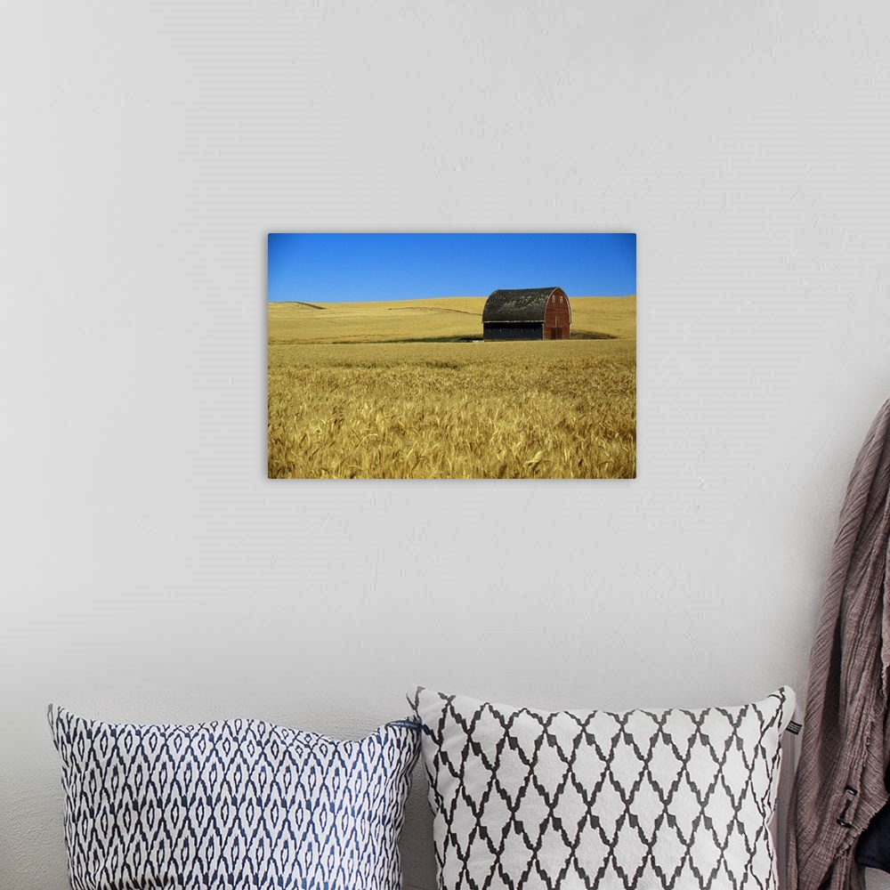A bohemian room featuring Large wall art of a barn in the middle of a field printed on canvas.