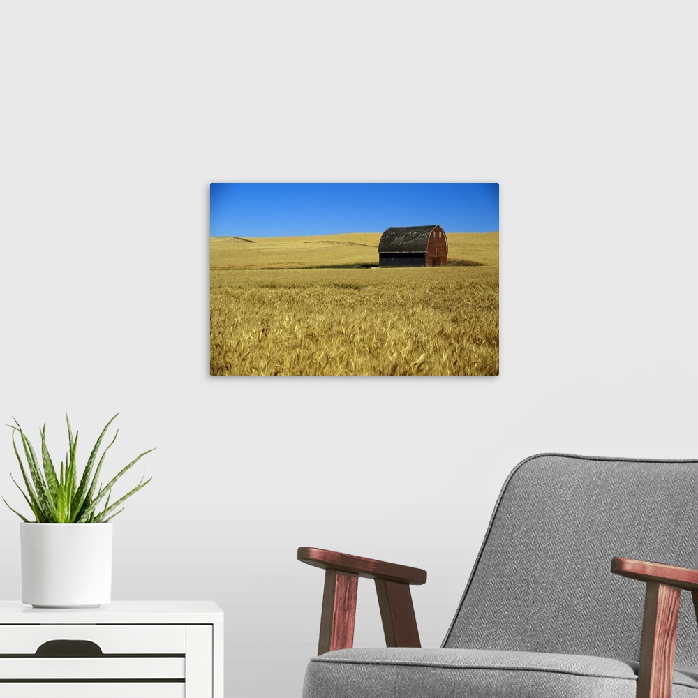 A modern room featuring Large wall art of a barn in the middle of a field printed on canvas.