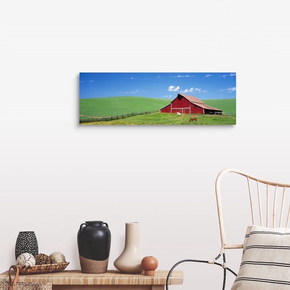 A farmhouse room featuring Empty farmland, gently rolling hills, and single structure with two horses photographed from a di...